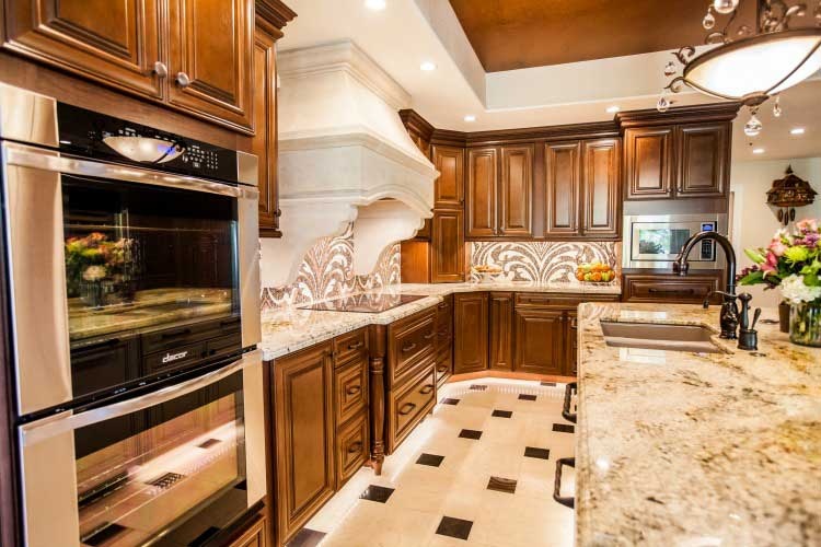 Kitchen Remodeling Contractor in Chandler, AZ. Luxurious kitchen renovation with two tones on wood cabinets, a large island, a stone cook-top hood and LED lighting.