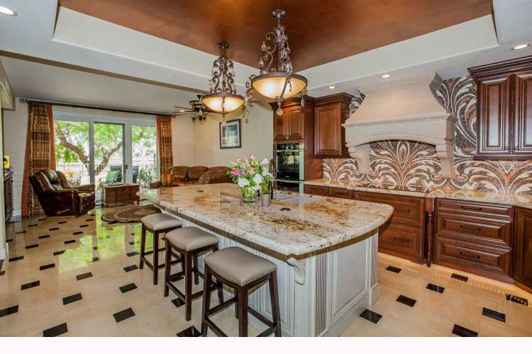 Kitchen Remodeling Contractor in Chandler, AZ. Luxurious kitchen renovation with two tones on wood cabinets, a large island, a stone cook-top hood and LED lighting.